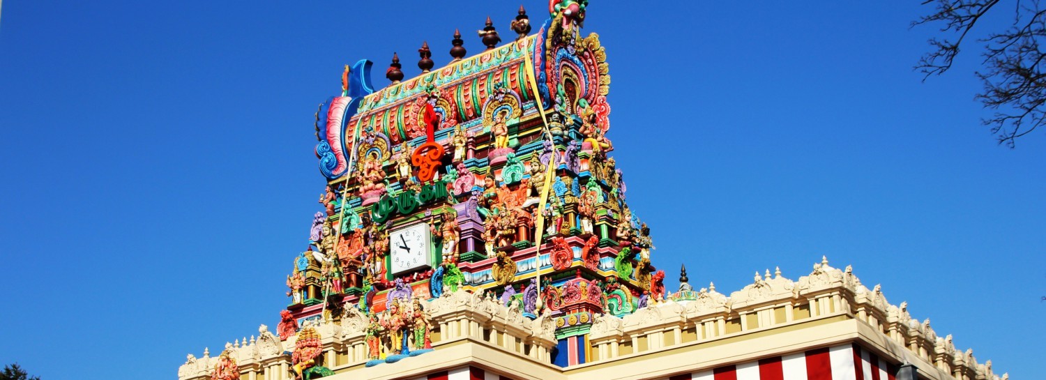 A detailed view of the roof of the temple with colorful and golden ornaments, as well as god figures.