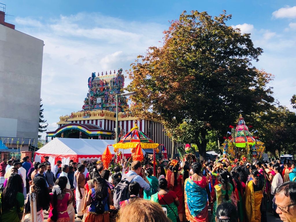 Several groups of people around the temple, dressed in traditional saris.