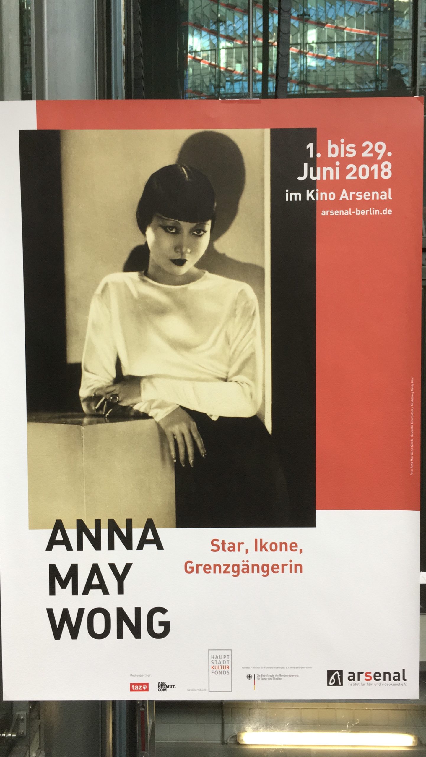 Eine schwarz, rot-weiße Fimpostkarte. Ein schwarz-weiß Bild von Anna May Wong ist zu sehen. Die Überschrift sagt “Anna May Wong, Star, Ikone Grenzgängerin”. Rechts oben steht “01. bis 29. Juni 2018 im Kino Arsenal”.