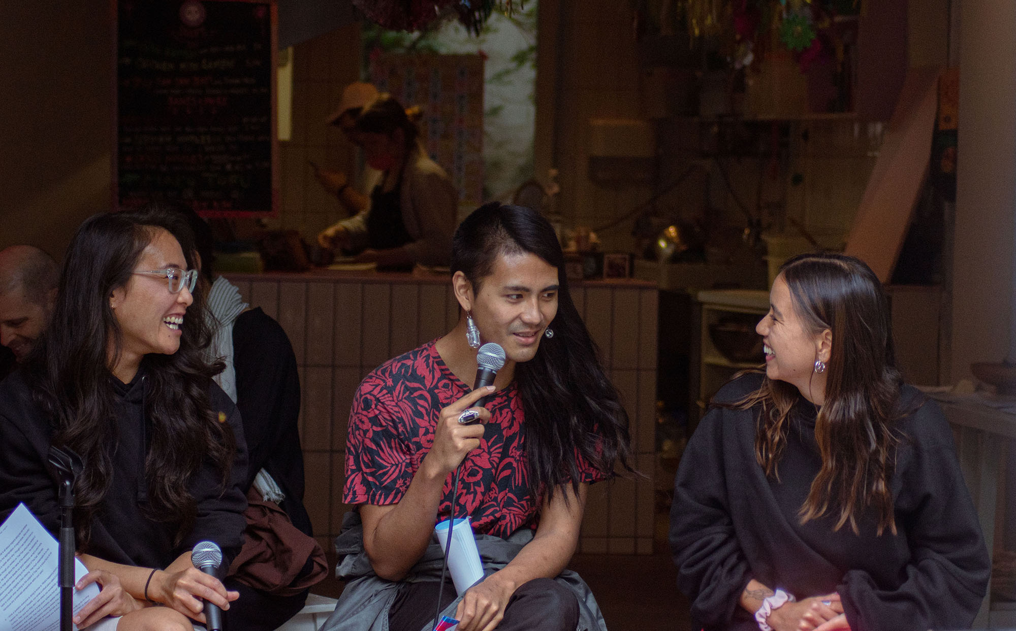 Vicky, Sarnt und Rosalia (v.l.n.r.) sitzen vor dem Pandanoodle Laden und lachen gemeinsam während des #Mygration Events vom 20.06.2020.